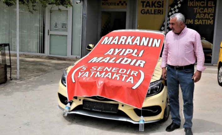 Aldığı lüks aracı işyerinin önüne koyup, üzerine “Markanın ayıplı malıdır, 5 yıldır yatmakta” yazdı